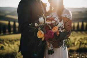 Close-up of a bride and groom embracing, holding a bouquet, against an Italian sunset