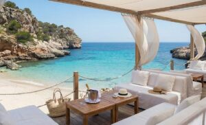 Luxury seaside wedding venue in Mallorca featuring a bohemian-chic dining table set on a cliffside terrace overlooking the turquoise Mediterranean sea